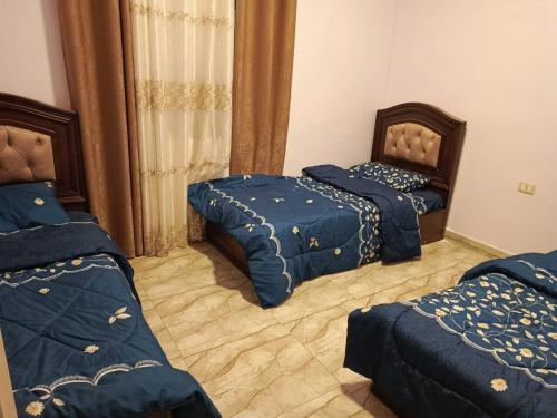 a bedroom with two beds with blue comforters at شاليه الاميرات in Sowayma