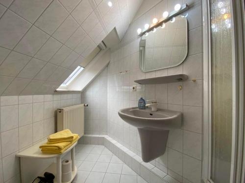 a white bathroom with a sink and a mirror at Stockrosenhuus in Westerland