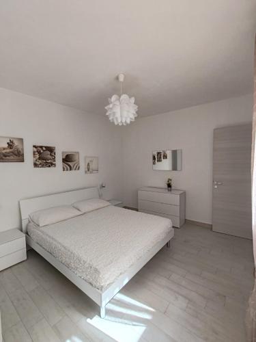 a white bedroom with a bed and a chandelier at GHETTO DELLE STELLE in Lampedusa