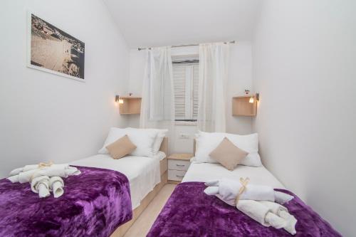 2 Betten in einem weißen Zimmer mit lila Bettwäsche in der Unterkunft Apartment Superb View 2 in Dubrovnik