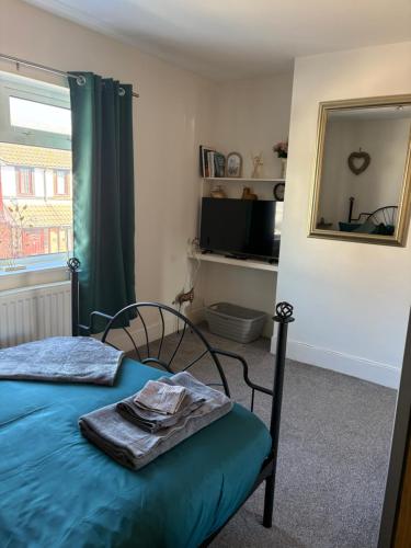 a bedroom with a bed with a blue blanket and a mirror at Valeries House 4 Bed 2 Bath close to beach in Gorleston-on-Sea