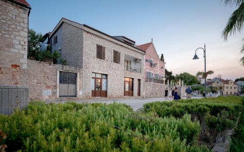 an old brick building with people walking down a street at Seafront Stone Home With King Beds, Garden And Balcony in Stari Grad