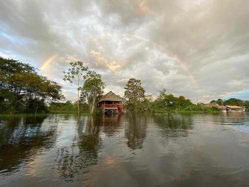 a rainbow in the middle of a river with a house at Casa Kukama Lodge in Iquitos