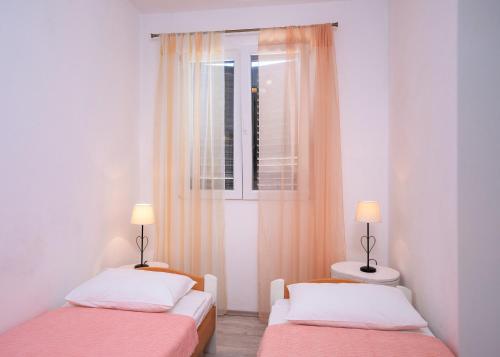 two beds in a small room with a window at Seafront Stone Home With King Beds, Garden And Balcony in Stari Grad