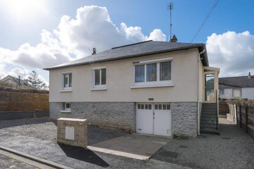 a white house with two garage doors and a fence at Le Jovia - Cour extérieure - Wifi in Laval