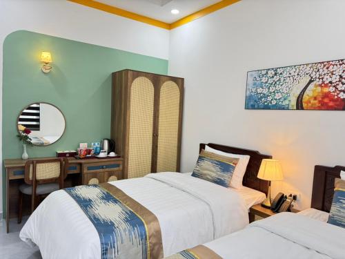 a bedroom with two beds and a desk with a computer at ORCHID Hotel in Da Lat