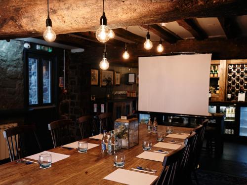 a large wooden table in a restaurant with a screen at Old Court House Inn in Saint Aubin