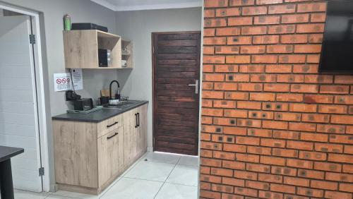 a kitchen with a brick wall next to a door at Pro Plants Accommodation in Kimberley
