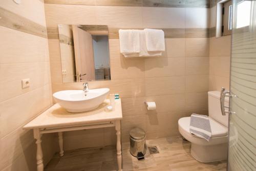 a bathroom with a toilet a sink and a bath tub at Santa Marina Hotel in Agios Nikitas