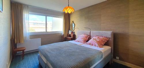 - une chambre avec un lit doté d'oreillers roses et d'une fenêtre dans l'établissement La Terrasse Ensoleillee, à Quiberon