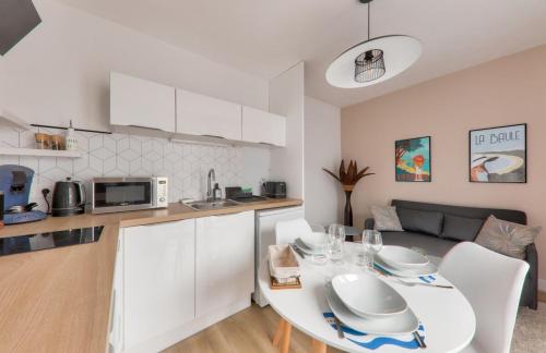 une cuisine et un salon avec une table et des chaises blanches dans l'établissement Jolie Maisonnette avec terrasse, à La Baule