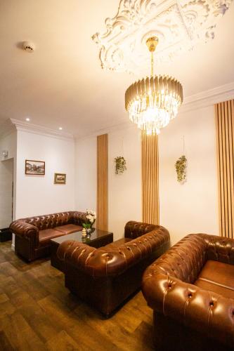 a living room with leather couches and a chandelier at Albert 1er in Albertville
