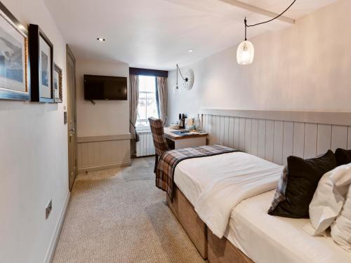 a bedroom with a bed and a desk and a television at Old Court House Inn in Saint Aubin