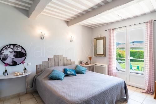 une chambre avec un lit avec des oreillers bleus et une fenêtre dans l'établissement La marinette, à Fontaine-de-Vaucluse