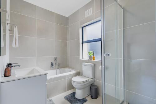 a bathroom with a toilet and a sink and a shower at Ballito Village Luxury Apartments in Ballito