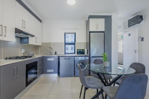 a kitchen with a glass table and chairs at Ballito Village Luxury Apartments in Ballito