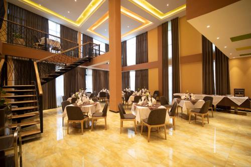a dining room with tables and chairs and windows at Vamos Addis Hotel in Addis Ababa