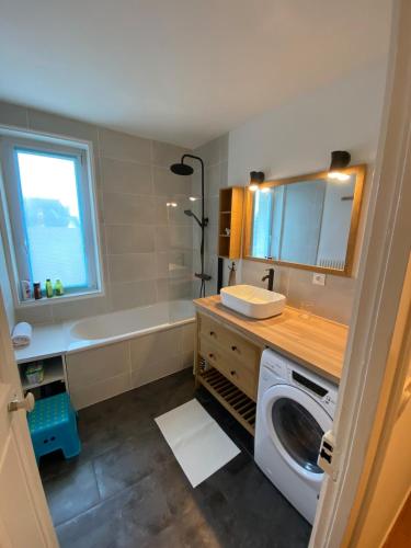 une salle de bain avec un lavabo et une machine à laver dans l'établissement Mon appartement vue mer, à Ouistreham