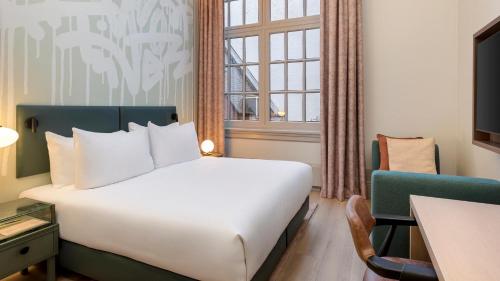 a hotel room with a bed and a window at The College Hotel Amsterdam, Autograph Collection in Amsterdam