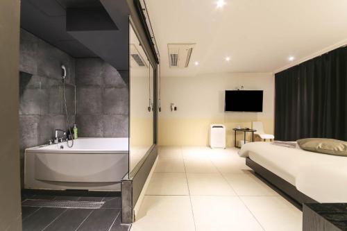 a bedroom with a tub and a bed and a television at Hotel Yaja Sasang Terminal in Busan