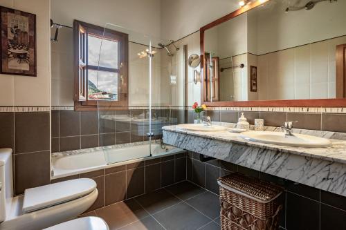 a bathroom with two sinks and a tub and a toilet at Casa Mariella en Linares, Ribadesella in Linares
