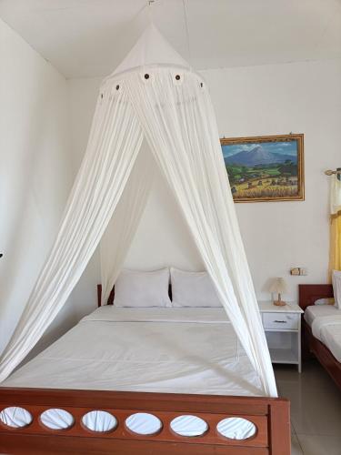 a canopy bed with white curtains in a bedroom at Moon view Bungalow's in Kelimutu