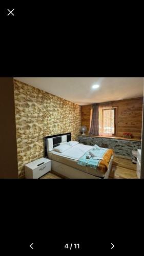 a bedroom with a bed and a brick wall at Svaneti in Lentekhi