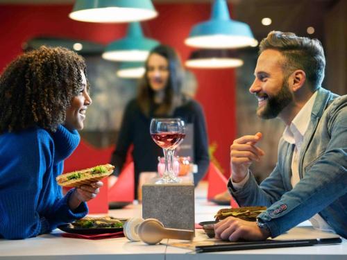 a man and a woman sitting at a table eating food at ibis Aberdeen Centre – Quayside in Aberdeen