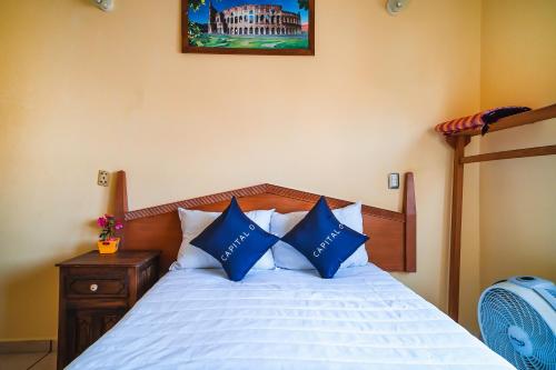a bedroom with a bed with blue and white pillows at Capital O Hotel Aurora, Tuxtla Gutiérrez in Tuxtla Gutiérrez