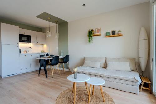 un salon avec un canapé et une table et une cuisine dans l'établissement Cocooning à 5 mn de la Grande Plage Parking privé, à Les Sables-dʼOlonne