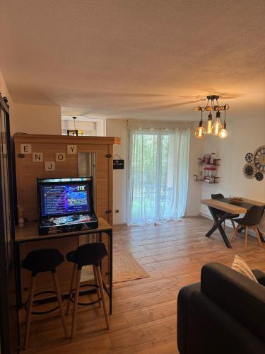 un salon avec une télévision sur une table et des chaises dans l'établissement T2, Balneo, sauna, lit rond, jeux arcades, parking, à Tournefeuille