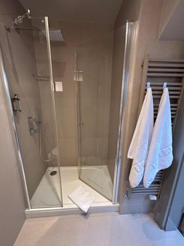 a shower with a glass door and towels in a bathroom at REZYDENCJA BOHEMA in Szczawno-Zdrój