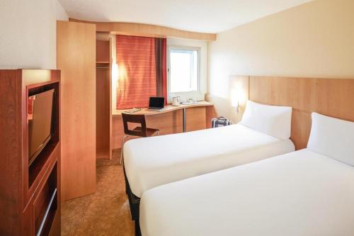a hotel room with two beds and a desk at ibis Aberdeen Centre – Quayside in Aberdeen