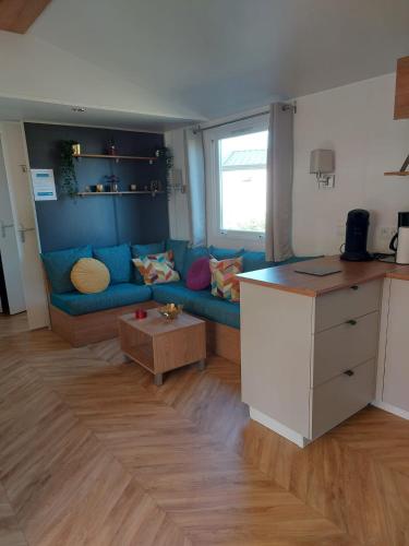 un salon avec un canapé bleu et une table dans l'établissement KOKUA VACANCES Mobil Homes Résidentiels camping 4 étoiles Lattes, à Lattes