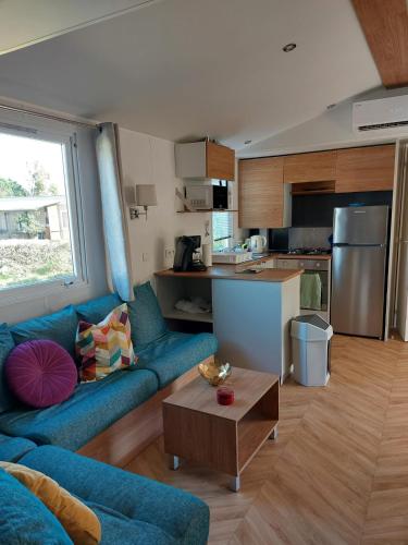 un salon avec un canapé bleu et une cuisine dans l'établissement KOKUA VACANCES Mobil Homes Résidentiels camping 4 étoiles Lattes, à Lattes