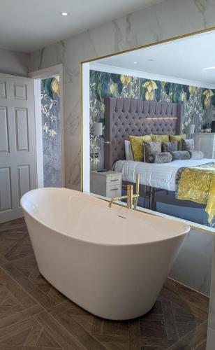 a white bath tub in a room with a bed at Glendower Hotel BW Signature Collection in Lytham St Annes