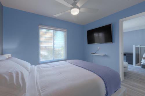 a blue bedroom with a bed with a ceiling fan at A Wave From It All Oceanview 2Nd Level Patio in Jacksonville Beach