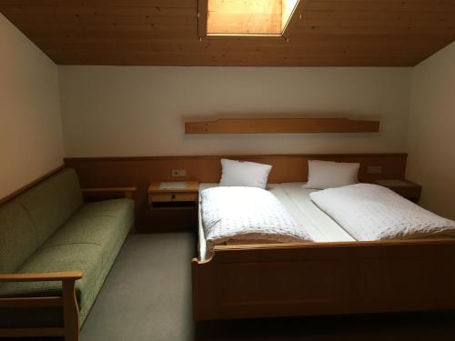 two beds in a room with a couch and a window at Hubergut Appartements in Radstadt