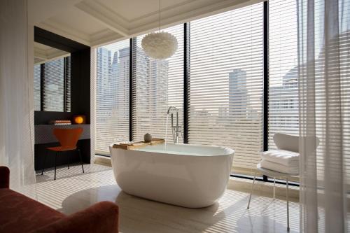 a bathroom with a tub in front of a large window at Signature by M Village Hai Bà Trưng in Ho Chi Minh City