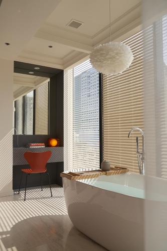 a bathroom with a tub and a red chair at Signature by M Village Hai Bà Trưng in Ho Chi Minh City