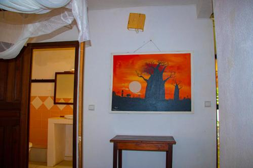 a painting on the wall of a room with a table at Résidence Kambana in Nosy Be