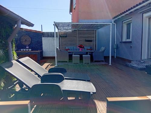 un patio avec des chaises et une table sur une terrasse dans l'établissement Maison au calme située à 10 minutes des plages, à Montescot