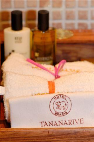 two towels on a shelf with a bottle of shampoo at Hotel Brajas in Antananarivo