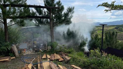a pile of smoke in a garden with a tree at Đen Hill Home The Wooden in Ðại Lào