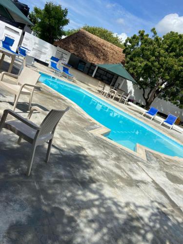 a swimming pool with a chair and a table and chairs at The Beach House by Maasai in Mombasa