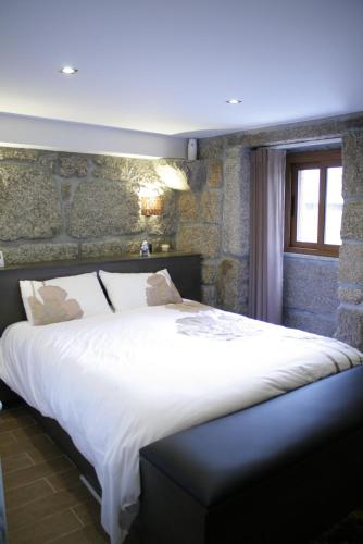 a large bed in a room with a stone wall at Casa da Fonte Gerês in Campo do Gerês