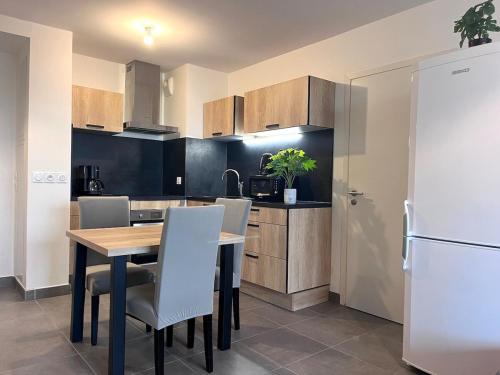 une cuisine avec une table, des chaises et un réfrigérateur dans l'établissement Bel appartement avec terrasse en bord de mer, à Mauguio