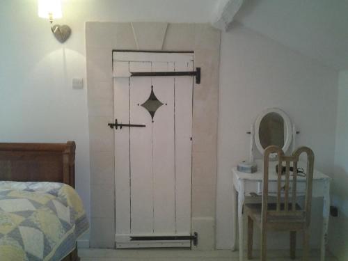 a bedroom with a door and a table and a chair at Jasmine cottage in Prinçay
