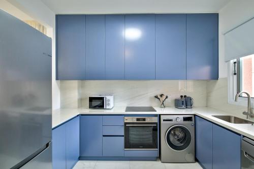 a kitchen with blue cabinets and a washer and dryer at Aphrodite Gardens Modern Villas by VICHY Holidays in Paphos