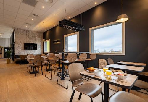 un restaurant avec des tables et des chaises et une grande fenêtre dans l'établissement B&B HOTEL Valenciennes Onnaing 3 étoiles, à Onnaing